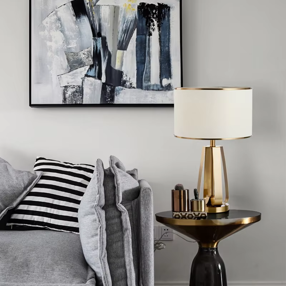 This is a light luxury geometric metal table lamp, featuring a gold polygonal hollow lamp base paired with an off-white fabric lampshade (with gold trim). It emits soft and warm light, serving both lighting and decorative purposes, suitable for bedroom nightstands, light luxury living room side tables, hotel guest rooms, showrooms and other scenarios.