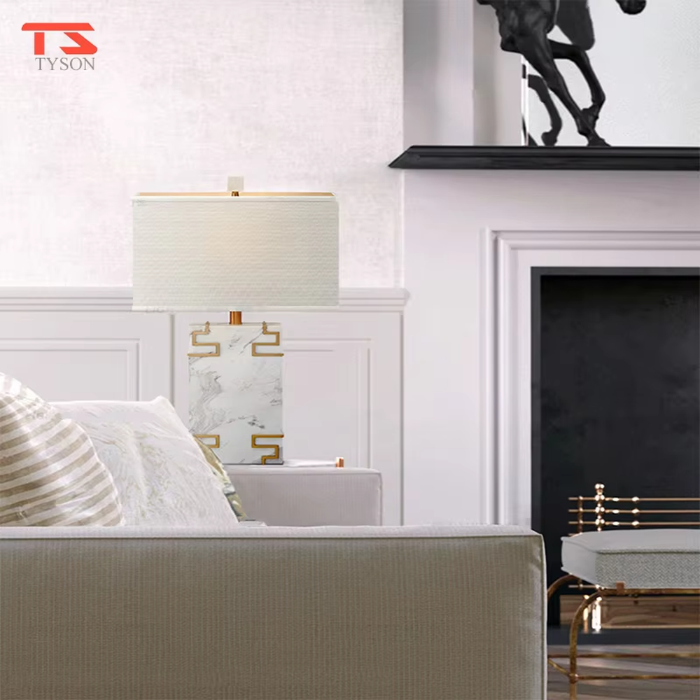 New Chinese light luxury style marble pattern table lamp, with a white faux marble lamp body paired with gold metal fretwork decoration, and a rectangular off-white fabric lampshade. It emits soft and elegant light, combining decorativeness and practicality, suitable for lighting and decoration in spaces such as bedroom nightstands, living room side tables, and New Chinese style show flats.