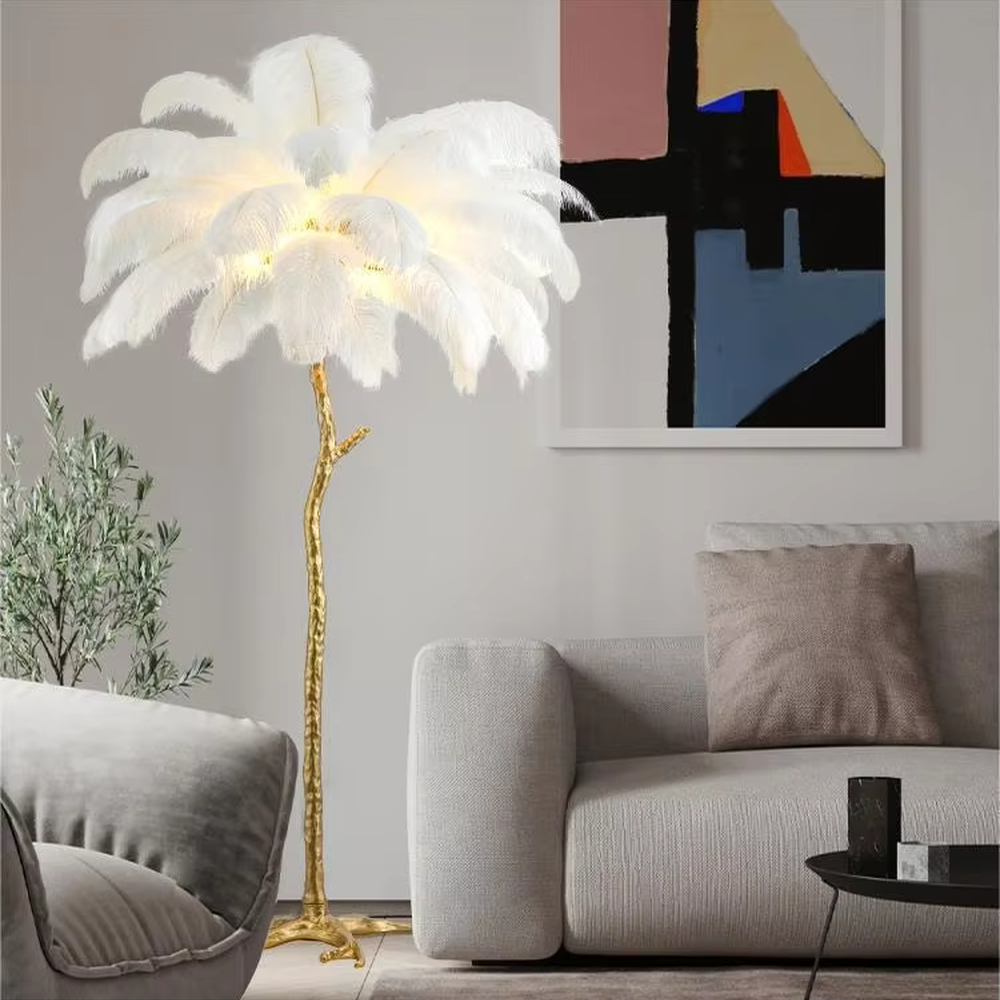 This is a luxury artistic floor lamp with a golden branch - shaped stand and a pink ostrich feather lampshade, featuring a romantic and luxurious design that shows elegant texture under warm light. It is used for space lighting and artistic decoration, combining practicality and aesthetics. It is suitable for modern luxury home living rooms, bedrooms, high - end hotel leisure areas, wedding photography scenes and other places.