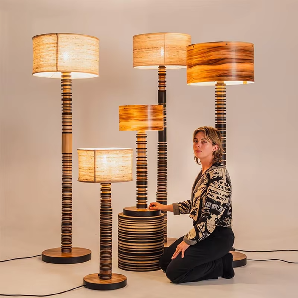 This is a natural retro-style wooden floor lamp, with a stand of alternating black and natural wood stripes and a wooden cylindrical lampshade, featuring a natural retro design and unique texture. It is used for space lighting and decoration, creating a natural and warm retro atmosphere. It is suitable for natural-style home living rooms, homestay leisure areas, art studios and other places.