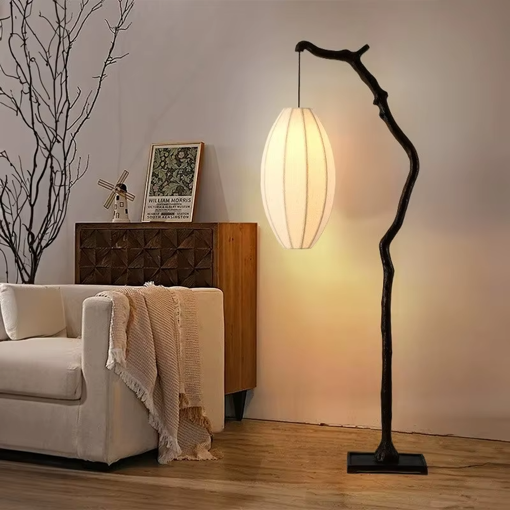 This is a new Chinese Zen-style floor lamp with a dark branch-shaped lamp pole and a beige fabric lantern lampshade. It features a natural and rustic design with a strong Zen sense. It is used for space lighting and decoration, creating a natural Zen ambiance. It is suitable for new Chinese-style home living rooms, Zen teahouses, art homestays and other places.