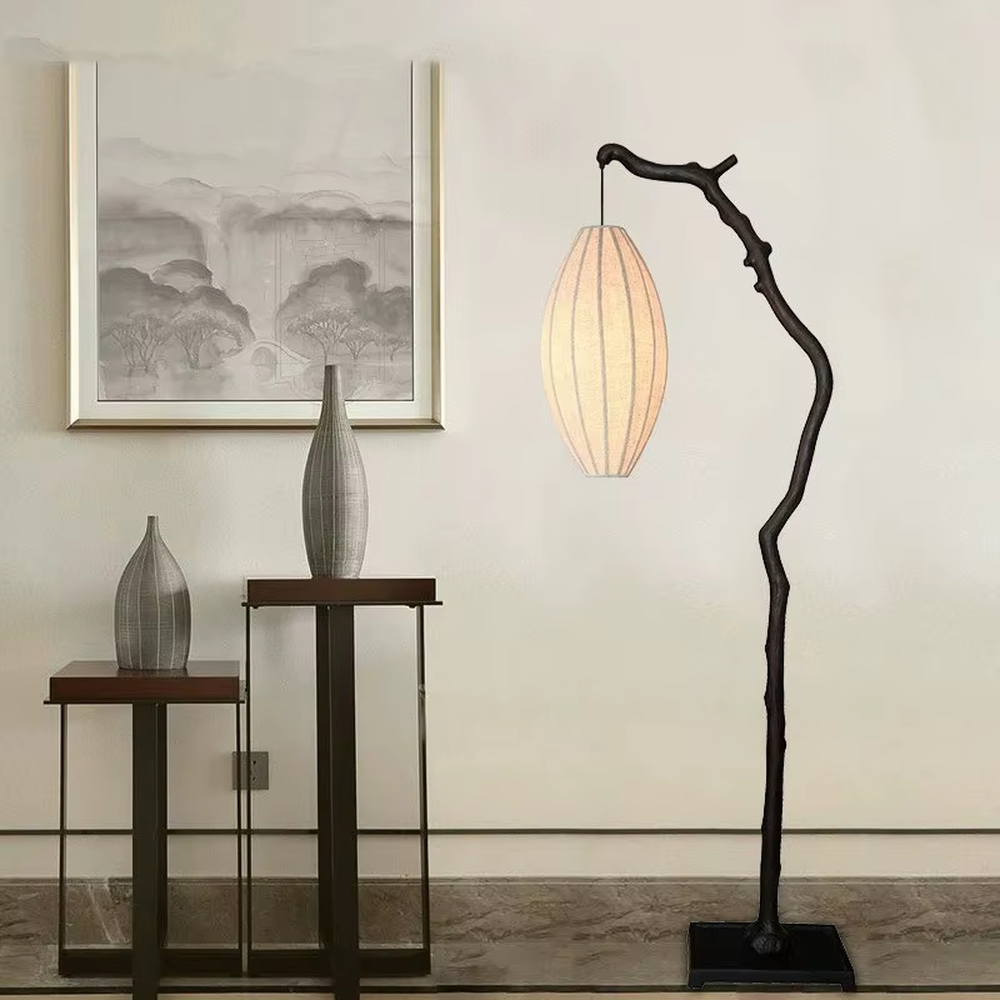This is a new Chinese Zen-style floor lamp with a dark branch-shaped lamp pole and a beige fabric lantern lampshade. It features a natural and rustic design with a strong Zen sense. It is used for space lighting and decoration, creating a natural Zen ambiance. It is suitable for new Chinese-style home living rooms, Zen teahouses, art homestays and other places.