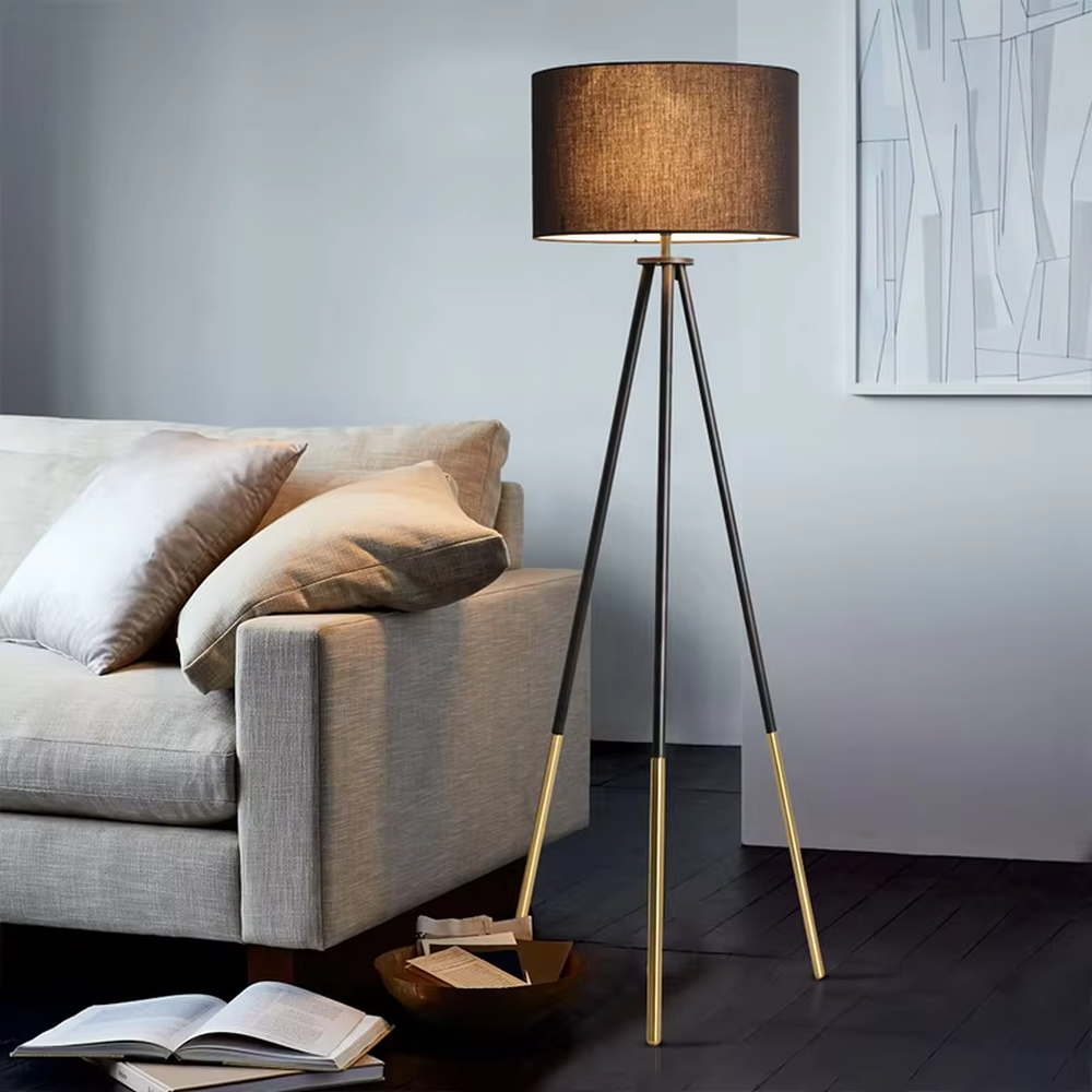 This is a modern tripod - shaped floor lamp with a black - gold metal tripod stand and a dark brown fabric cylindrical lampshade, featuring a minimalist luxury design with strong modern sense. It is used for space lighting and decoration, creating a warm and luxurious atmosphere. It is suitable for modern home living rooms, luxury - style residences, leisure reading areas and other places.