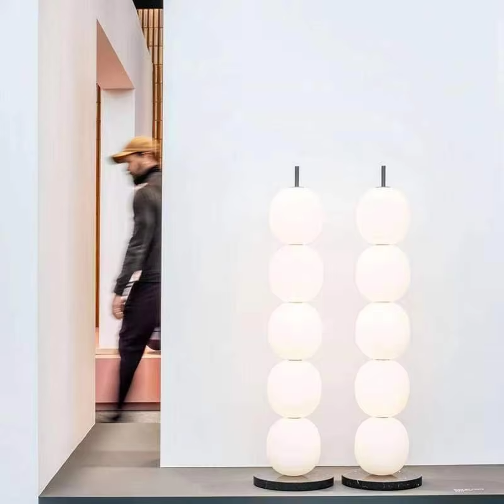 This is a modern minimalist multi-layer spherical glass floor lamp, with a black base and multiple white spherical glass lampshades stacked vertically. It features a minimalist and grand design, with soft and uniform lighting. It is used for space ambient lighting and decoration, creating a modern minimalist and warm atmosphere. Suitable for modern minimalist living rooms, Nordic-style homes, art studios and other places.