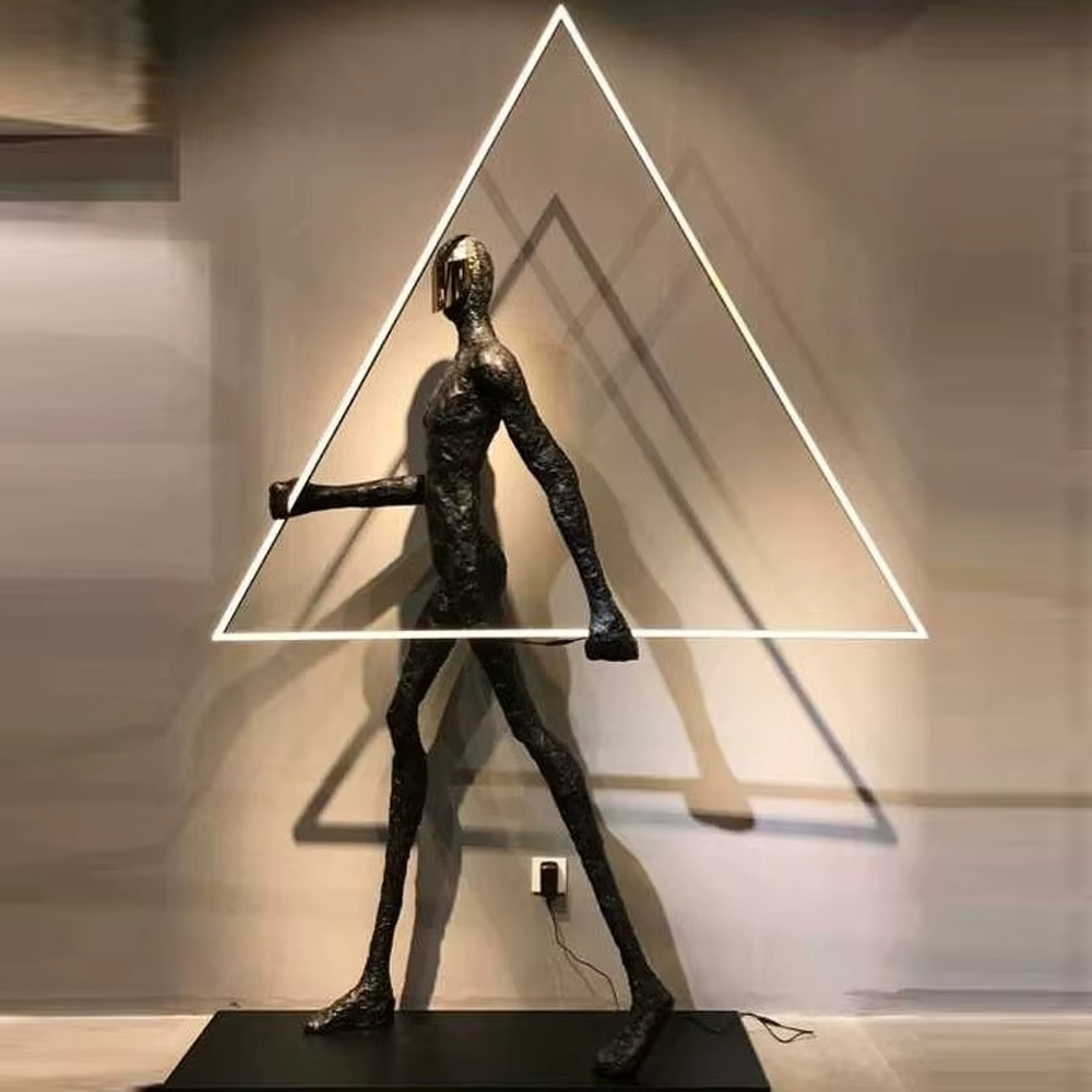 This is an artistic installation-style human sculpture ring floor lamp, featuring a black human sculpture shape paired with a circular LED light. It has a strong sense of art and avant-garde, with soft lighting and visual impact. It is used for space lighting and artistic decoration, creating a modern artistic and avant-garde atmosphere. Suitable for art exhibition halls, high-end villa living rooms, designer studios and other places.