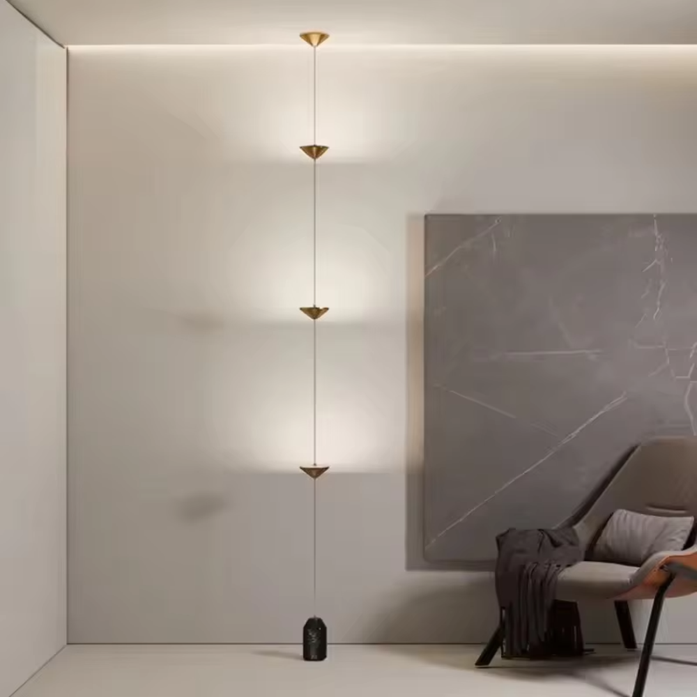 This is a modern artistic golden conical long-string chandelier, with multiple golden conical lamp bodies connected in series and a black marble base, featuring a minimalist artistic design and modern style. It is used for space lighting and decoration, creating an artistic and modern atmosphere. Suitable for modern art home stairwells, high-ceilinged living rooms, designer studios and other places.