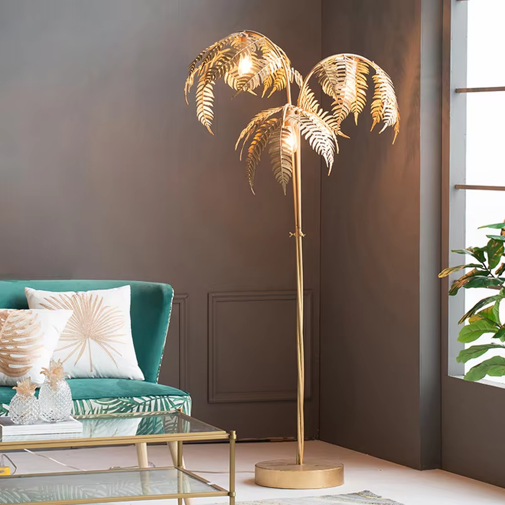 This is a tropical artistic floor lamp with golden palm leaf-shaped lamp heads and a metal pole, featuring a strong tropical artistic sense. It is used for space lighting and decoration, creating a tropical artistic atmosphere. It is suitable for tropical-style home living rooms, creative cafes, art homestays and other places.