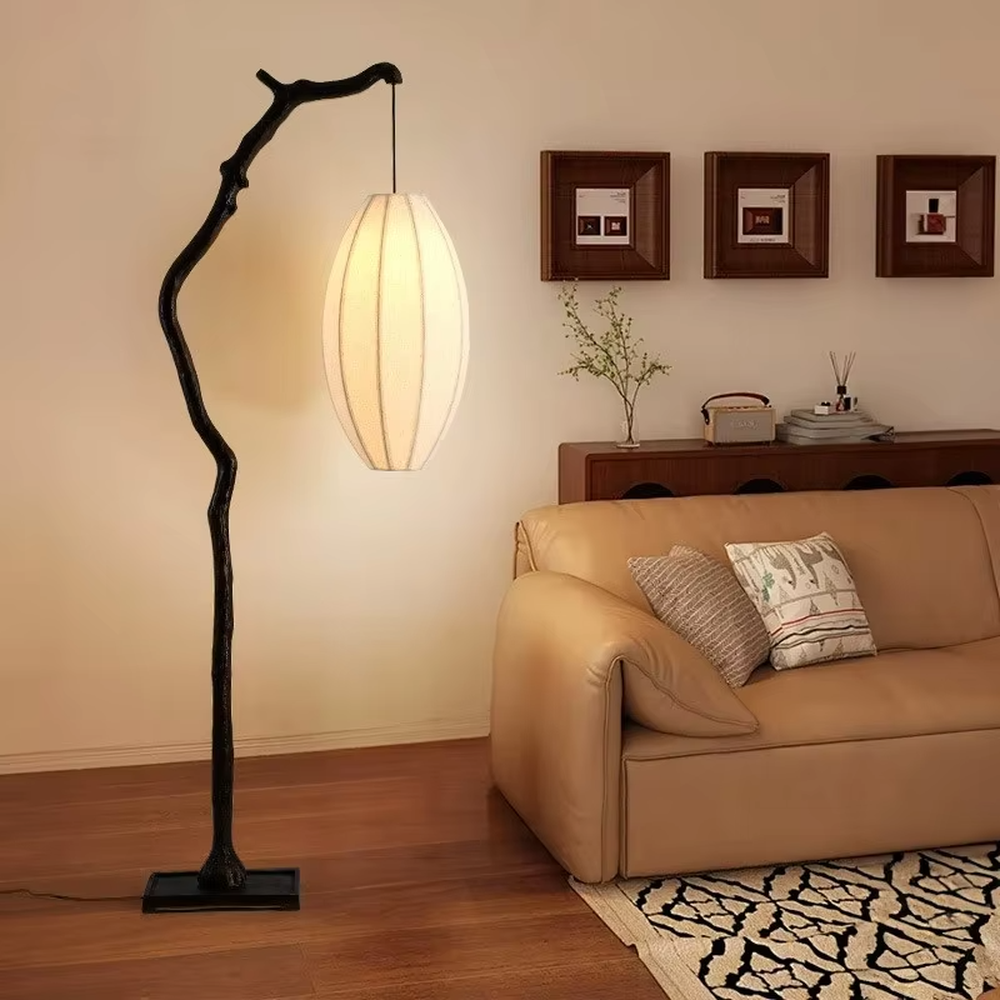 This is a new Chinese Zen-style floor lamp with a dark branch-shaped lamp pole and a beige fabric lantern lampshade. It features a natural and rustic design with a strong Zen sense. It is used for space lighting and decoration, creating a natural Zen ambiance. It is suitable for new Chinese-style home living rooms, Zen teahouses, art homestays and other places.
