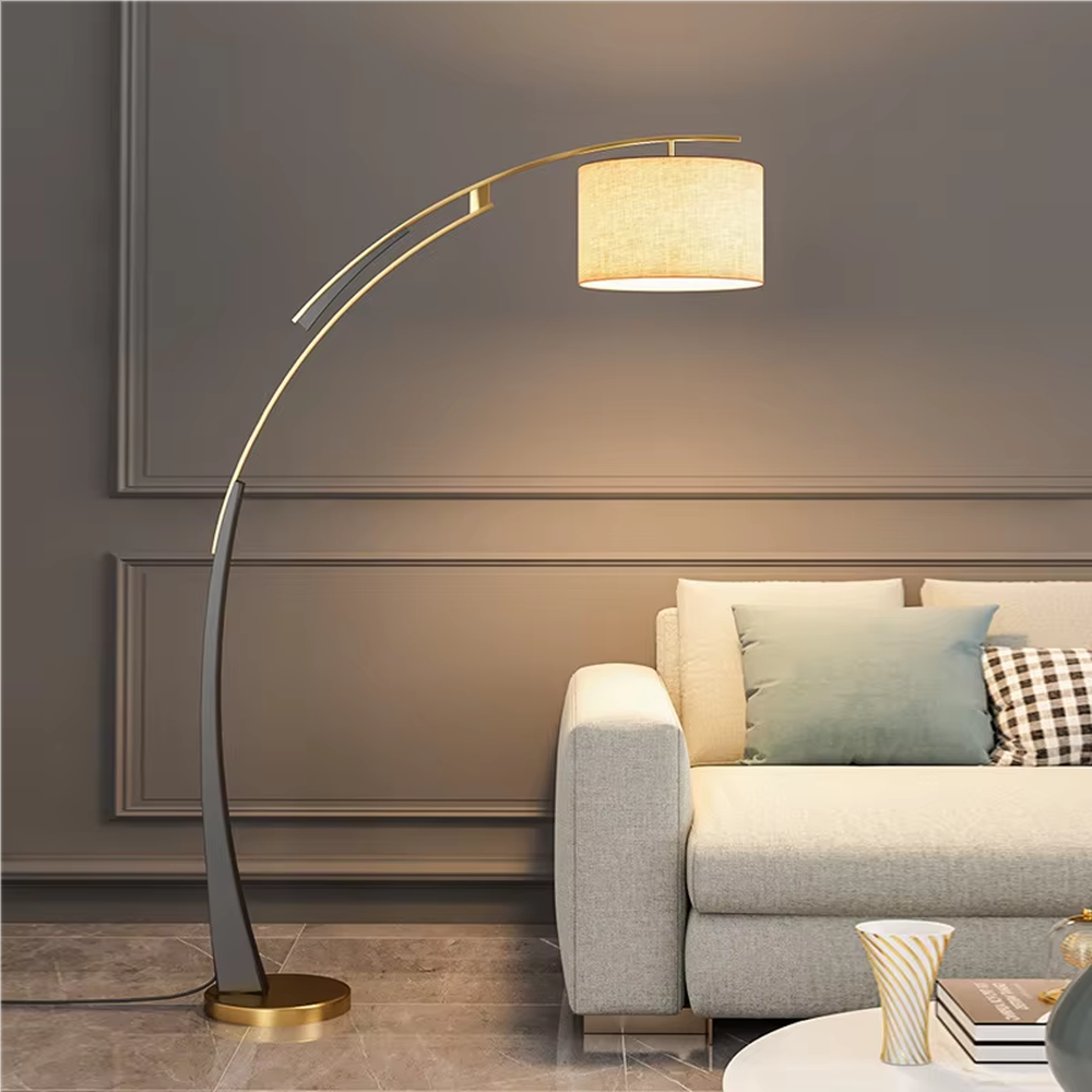 This is a modern arc luxury floor lamp, with a black-gold arc metal stand, a beige fabric cylindrical lampshade, and a golden base, featuring a minimalist and grand design with strong luxury texture. It is used for space lighting and decoration, creating a warm luxury atmosphere. It is suitable for modern home living rooms, luxury-style residences, leisure reading areas and other places.