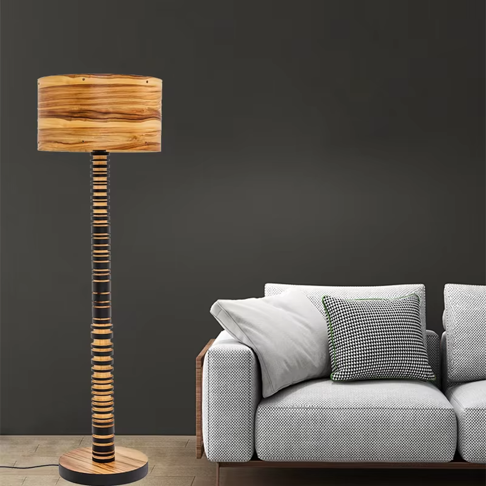 This is a natural retro-style wooden floor lamp, with a stand of alternating black and natural wood stripes and a wooden cylindrical lampshade, featuring a natural retro design and unique texture. It is used for space lighting and decoration, creating a natural and warm retro atmosphere. It is suitable for natural-style home living rooms, homestay leisure areas, art studios and other places.