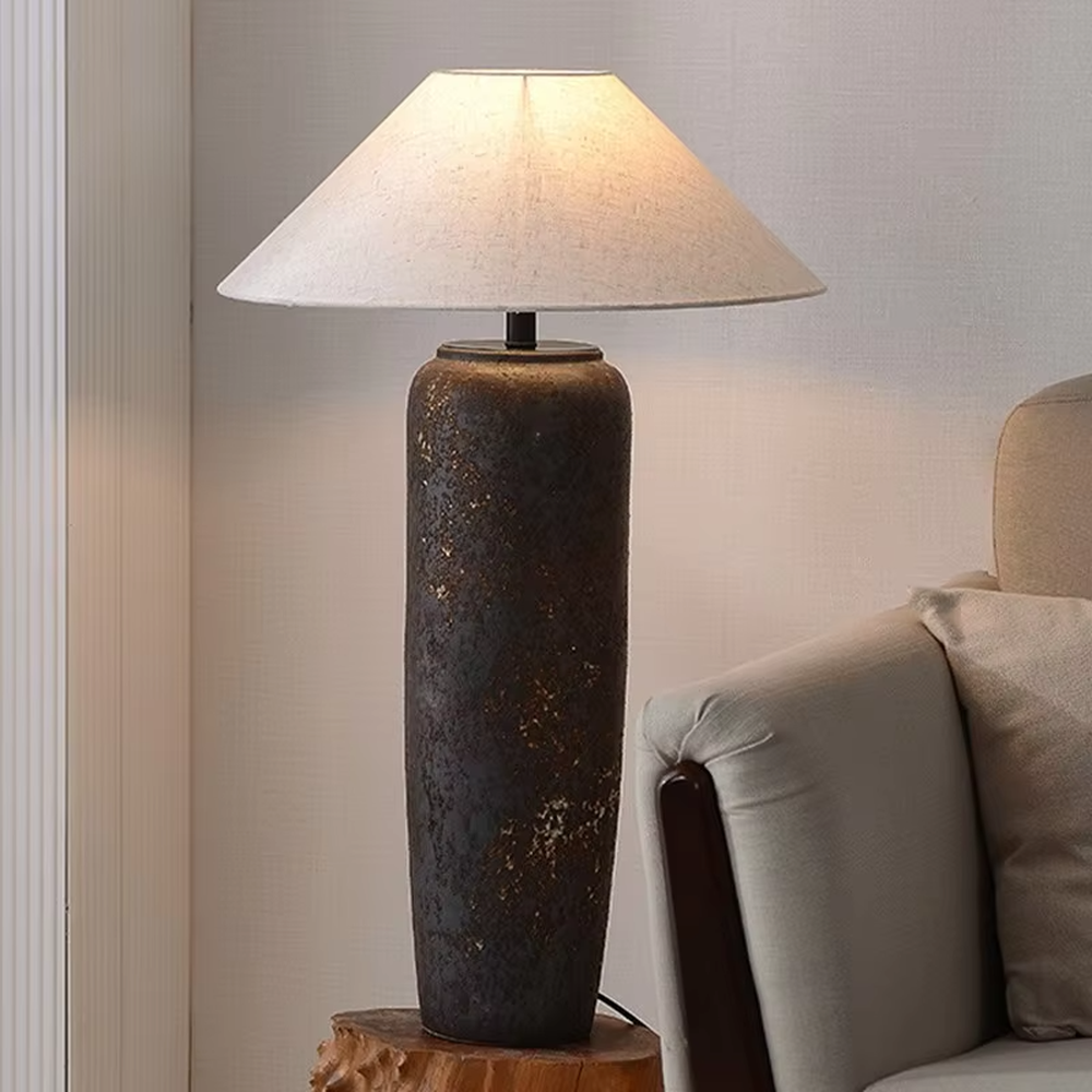 This is a retro industrial-style floor lamp with a dark brown aged texture lamp post and a white fabric slanted lampshade. It features a retro and rustic design with industrial texture. It is used for space lighting and decoration, creating a retro industrial atmosphere. It is suitable for retro industrial-style home living rooms, loft-style apartments, art studios and other places.