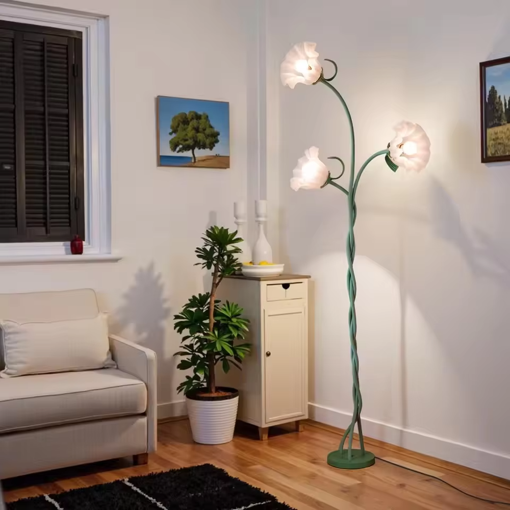 This is a natural artistic flower-shaped floor lamp, with a green spiral metal stand and three white flower-shaped lampshades, featuring a strong natural artistic sense and fresh elegant style. It is used for space lighting and decoration, creating a natural artistic atmosphere. It is suitable for pastoral-style home living rooms, homestay leisure areas, art studios and other places.
