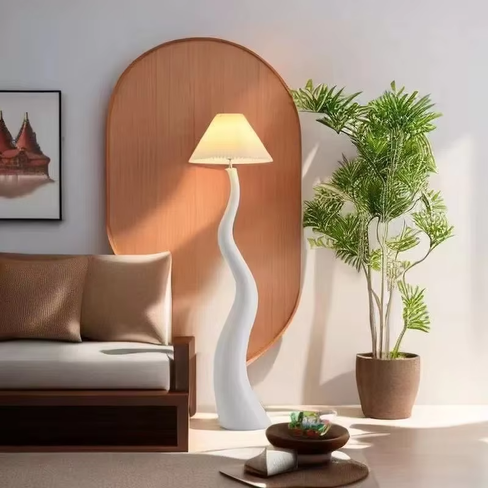This is a natural artistic wooden curved floor lamp, with a light wood irregular curved bracket and a pleated fabric lampshade, featuring a strong sense of art and natural atmosphere. It is used for space lighting and decoration, creating a natural artistic ambiance. It is suitable for Nordic-style home living rooms, art homestays, creative studios and other places.