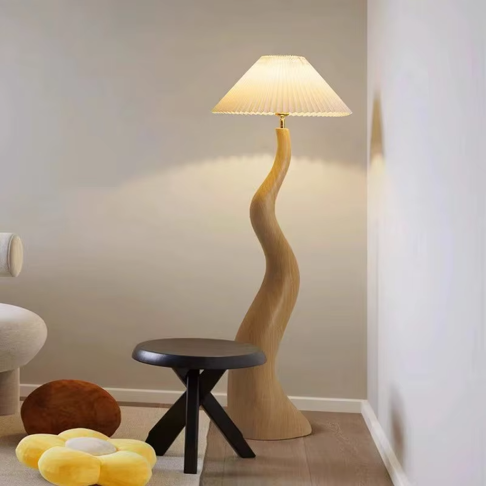This is a natural artistic wooden curved floor lamp, with a light wood irregular curved bracket and a pleated fabric lampshade, featuring a strong sense of art and natural atmosphere. It is used for space lighting and decoration, creating a natural artistic ambiance. It is suitable for Nordic-style home living rooms, art homestays, creative studios and other places.