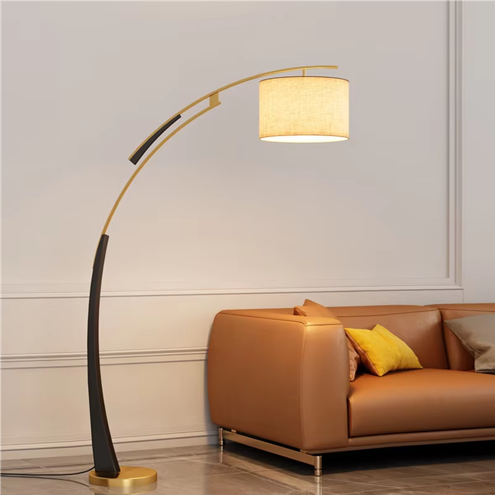 This is a modern arc luxury floor lamp, with a black-gold arc metal stand, a beige fabric cylindrical lampshade, and a golden base, featuring a minimalist and grand design with strong luxury texture. It is used for space lighting and decoration, creating a warm luxury atmosphere. It is suitable for modern home living rooms, luxury-style residences, leisure reading areas and other places.