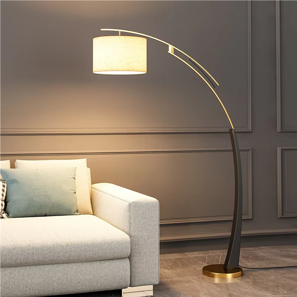 This is a modern luxury arc floor lamp, with a black-gold arc metal stand, a beige fabric cylindrical lampshade, and a golden base, featuring a minimalist and grand design with strong luxury texture. It is used for space lighting and decoration, creating a warm luxury atmosphere. It is suitable for modern luxury home living rooms, leisure reading areas, high-end hotel guest rooms and other places.