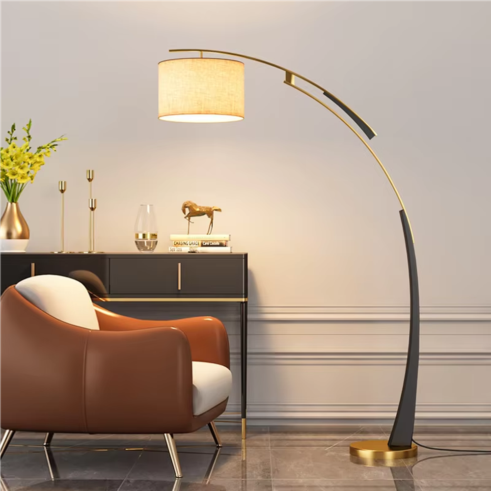 This is a modern arc luxury floor lamp, with a black-gold arc metal stand, a beige fabric cylindrical lampshade, and a golden base, featuring a minimalist and grand design with strong luxury texture. It is used for space lighting and decoration, creating a warm luxury atmosphere. It is suitable for modern home living rooms, luxury-style residences, leisure reading areas and other places.