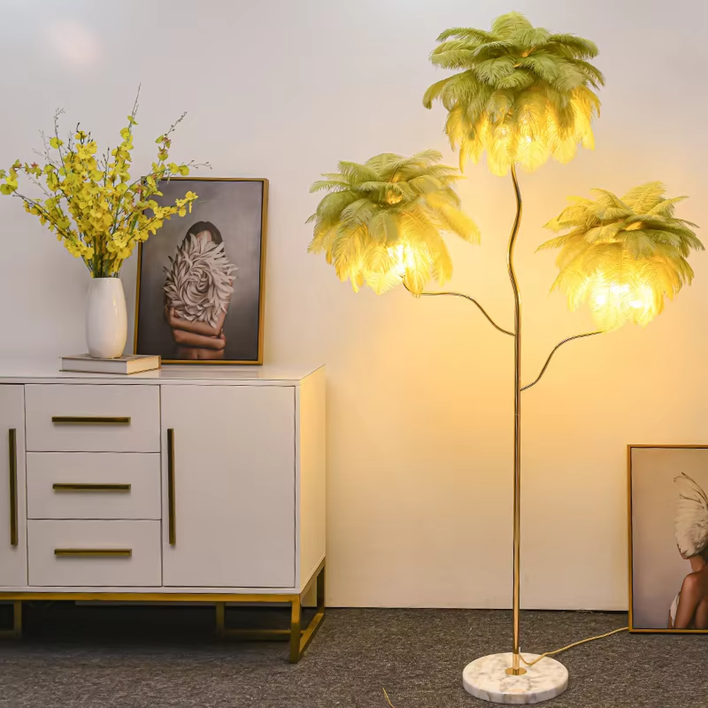This is a light luxury soft feather-shaped floor lamp, equipped with three white feather lampshades, paired with a golden curved lamp pole and a marble base. The design is gentle and elegant, with soft and hazy lighting through the feathers. It is used for space lighting and decoration, creating a warm and soft light luxury atmosphere. Suitable for light luxury-style living rooms, bedrooms, internet-famous homestays and other places.