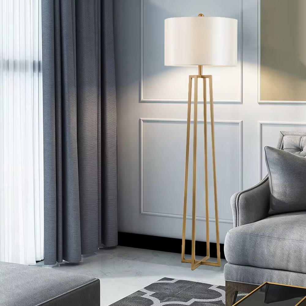 This is a light luxury minimalist golden geometric frame floor lamp, featuring a golden triangular geometric frame lamp pole paired with a white cylindrical fabric lampshade. It has a minimalist and grand design, with soft and uniform lighting. It is used for space lighting and decoration, creating a light luxury minimalist atmosphere. Suitable for light luxury-style living rooms, modern minimalist bedrooms, high-end apartments and other places.