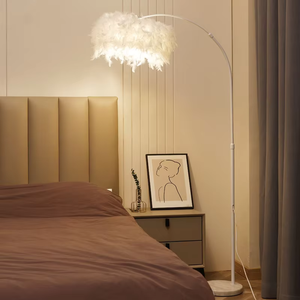 Warm romantic-style black curved feather floor lamp, white feather lampshade paired with black curved lamp pole and disc base, soft and warm lighting, creating a comfortable romantic space atmosphere.