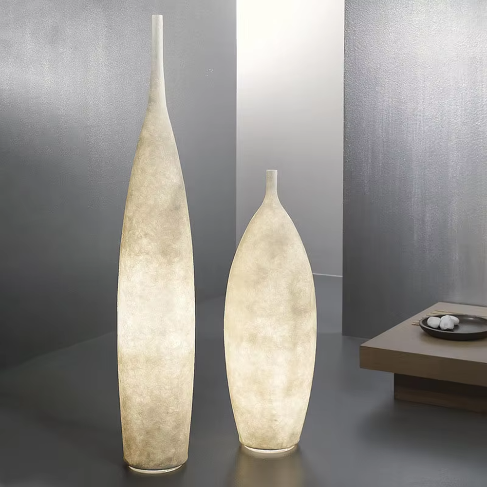 This is a Zen minimalist bottle-shaped paper art floor lamp (including large and small styles), made of light beige paper art texture material to create a slender bottle shape, with a large and small combination design. The light through the material is soft and hazy, creating a quiet and elegant atmosphere. It is used for space lighting and decoration, suitable for Zen-style spaces, minimalist homes and other places.