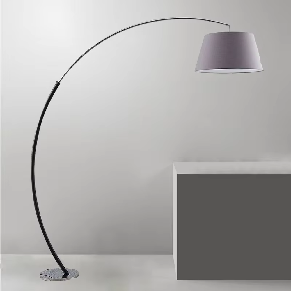 This is a modern minimalist curved floor lamp, with a black curved lamp pole paired with a light purple fabric lampshade and a silver textured disc base. The lighting is soft and warm, creating a minimalist comfortable atmosphere.