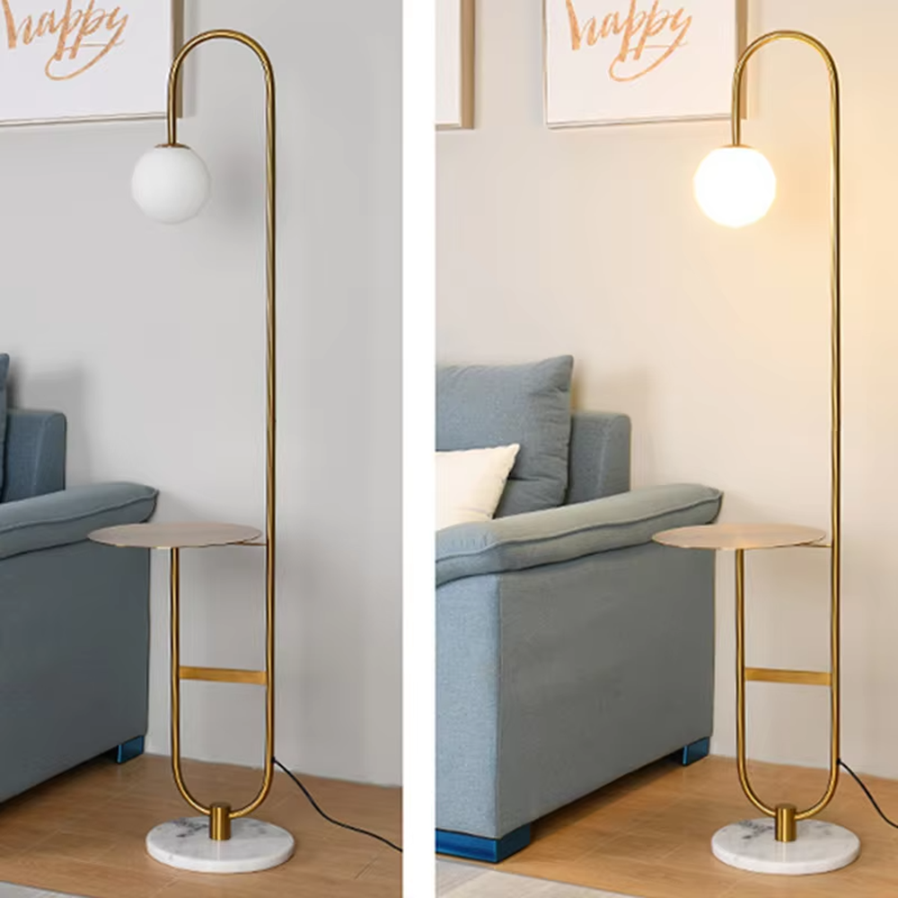 Modern light luxury golden curved floor lamp with table, white spherical lampshade + marble-patterned base, soft lighting, integrating lighting and storage functions, creating a minimalist high-end atmosphere.