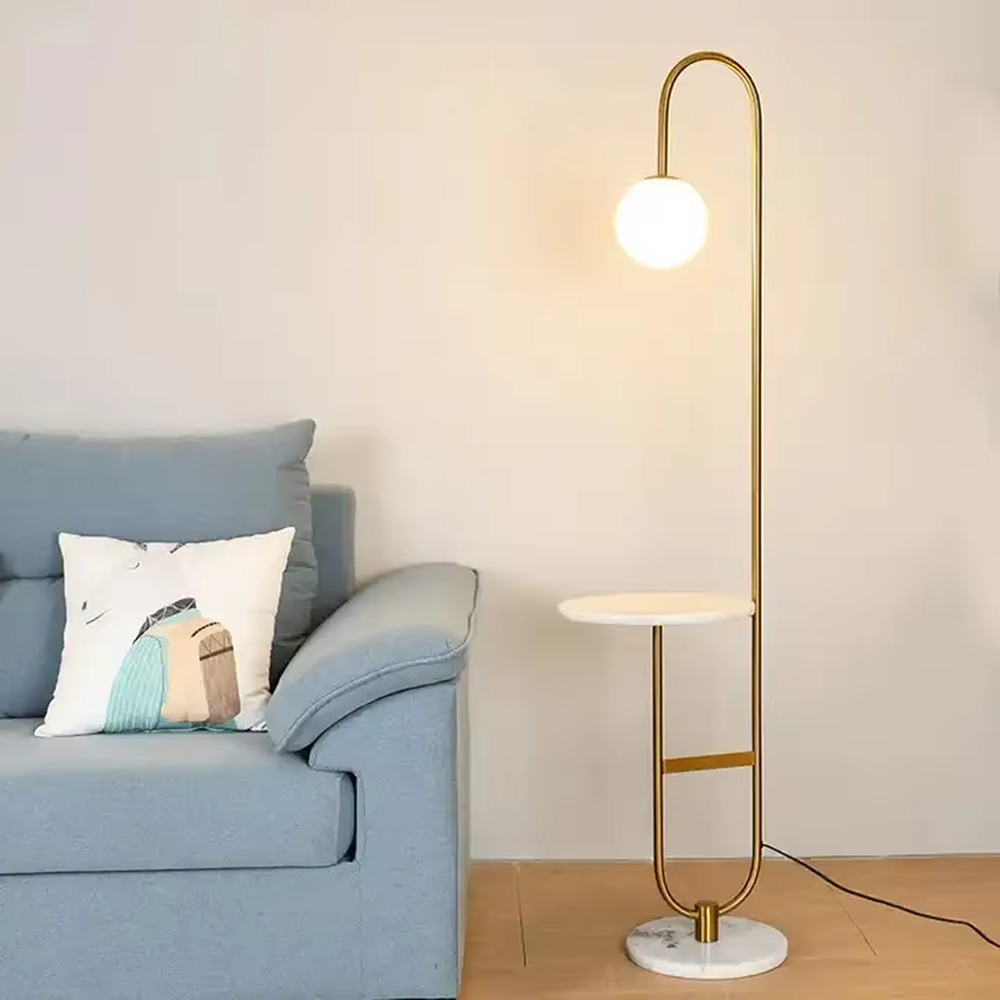 Modern light luxury golden curved floor lamp with table, white spherical lampshade + marble-patterned base, soft lighting, integrating lighting and storage functions, creating a minimalist high-end atmosphere.