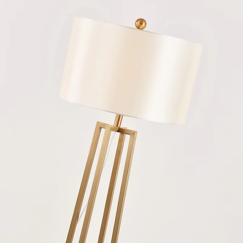 This is a light luxury minimalist golden geometric frame floor lamp, featuring a golden triangular geometric frame lamp pole paired with a white cylindrical fabric lampshade. It has a minimalist and grand design, with soft and uniform lighting. It is used for space lighting and decoration, creating a light luxury minimalist atmosphere. Suitable for light luxury-style living rooms, modern minimalist bedrooms, high-end apartments and other places.