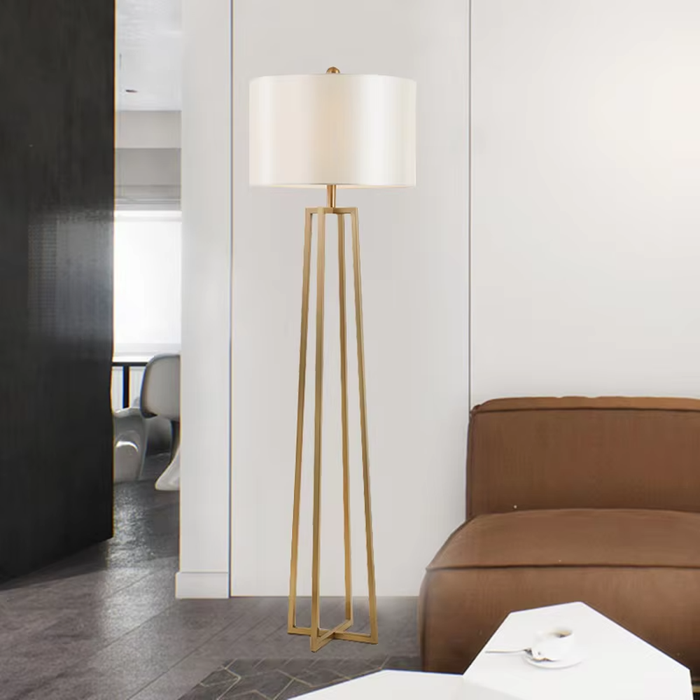 This is a light luxury minimalist golden geometric frame floor lamp, featuring a golden triangular geometric frame lamp pole paired with a white cylindrical fabric lampshade. It has a minimalist and grand design, with soft and uniform lighting. It is used for space lighting and decoration, creating a light luxury minimalist atmosphere. Suitable for light luxury-style living rooms, modern minimalist bedrooms, high-end apartments and other places.