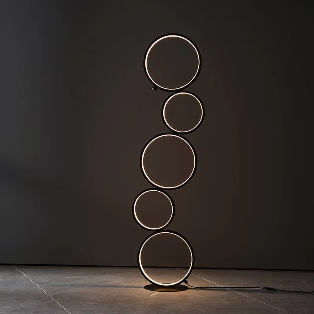 Modern art-style multi-layer luminous ring floor lamp, black frame + warm light ring light source + stacked shape, creating a simple artistic space atmosphere.