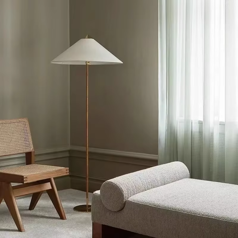 Light luxury vintage-style golden woven pole cone lampshade floor lamp, white cone fabric lampshade + golden disc base, soft lighting, creating an elegant vintage atmosphere.