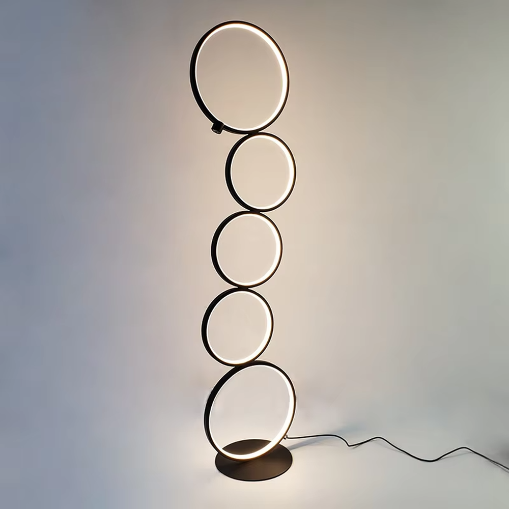 Modern art-style multi-layer luminous ring floor lamp, black frame + warm light ring light source + stacked shape, creating a simple artistic space atmosphere.