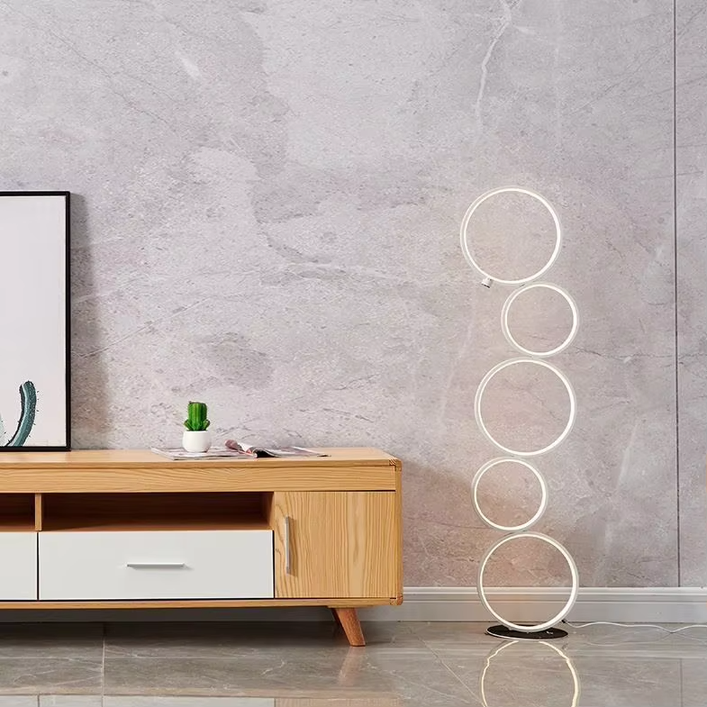 Modern art-style multi-layer luminous ring floor lamp, black frame + warm light ring light source + stacked shape, creating a simple artistic space atmosphere.