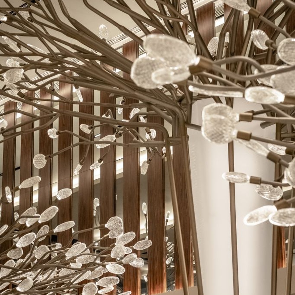 This new Chinese artistic tree-shaped chandelier features a metal branch frame paired with transparent light-emitting leaf-shaped ornaments, presenting a visual effect of blooming flower trees, serving both lighting and decorative purposes, suitable for large spaces such as hotel lobbies and high-end clubs.