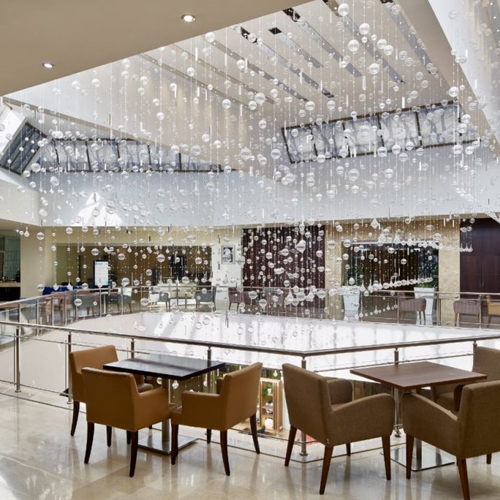 This large artistic bubble chandelier is composed of a large number of transparent glass bubble balls hung in a staggered manner by metal wires, presenting a visual effect like scattered starry sky. The light refracts through the bubbles to emit soft and transparent light spots, serving both lighting and decorative purposes, suitable for high-ceiling commercial spaces such as hotel lobbies and shopping mall atriums.