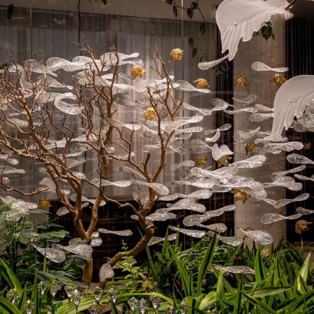 This is a natural-style suspended art installation lamp, composed of transparent ripple-shaped leaves and gold accents, creating an immersive scene with dead trees and green plants, with both decorative and lighting functions, ideal for weddings, high-end restaurants, art galleries and other scenarios.