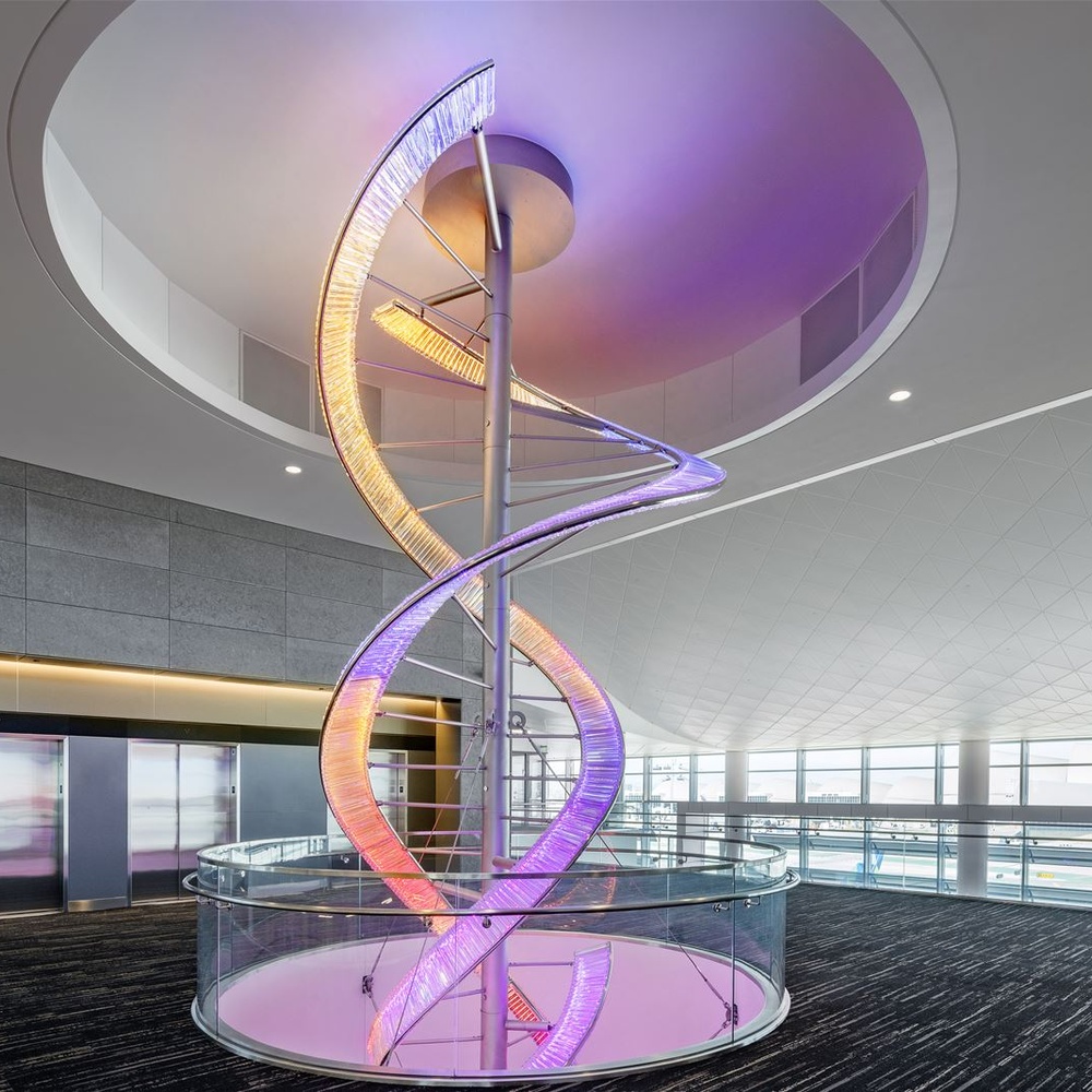 This is a large suspended art installation lamp, supported by a metal frame with blue-purple-cyan gradient LED light strips, featuring an abstract spiral and crescent shape, with both decorative and lighting functions, ideal as artistic decorative lighting for public spaces.