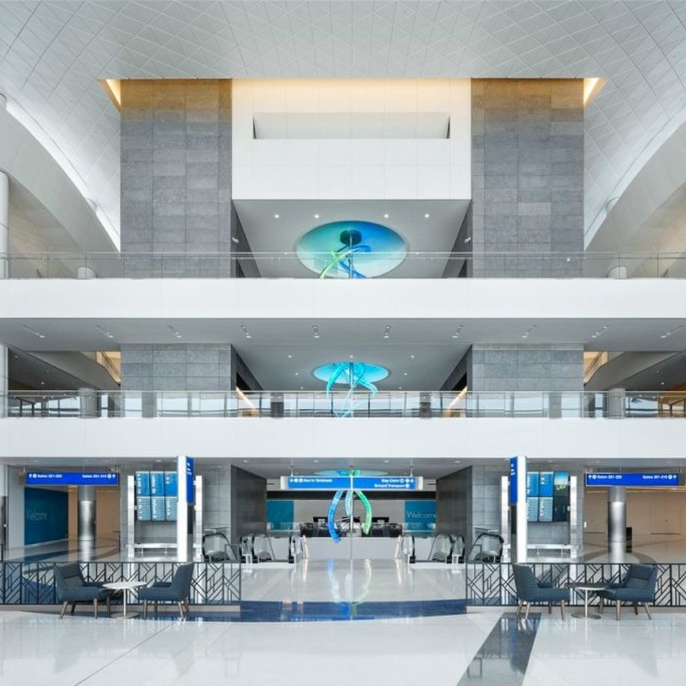 This is a large suspended art installation lamp, supported by a metal frame with blue-purple-cyan gradient LED light strips, featuring an abstract spiral and crescent shape, with both decorative and lighting functions, ideal as artistic decorative lighting for public spaces.