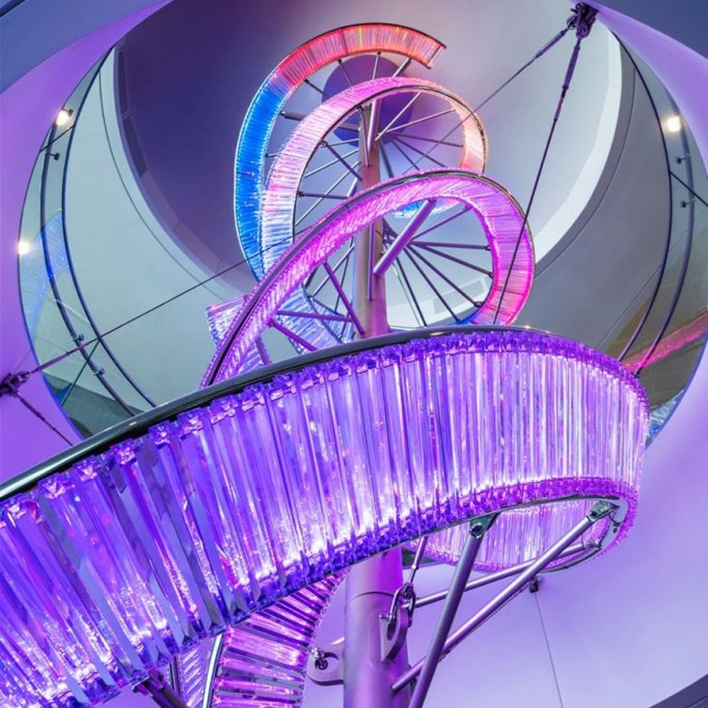 This is a large suspended art installation lamp, supported by a metal frame with blue-purple-cyan gradient LED light strips, featuring an abstract spiral and crescent shape, with both decorative and lighting functions, ideal as artistic decorative lighting for public spaces.