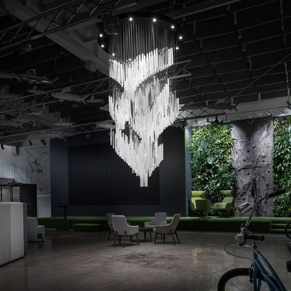 This modern industrial-style art chandelier consists of a large number of white acrylic strips hung staggered by metal wires, extending downward in a waterfall shape from a circular ceiling plate. Light passes through the strips to emit a transparent and soft halo, serving both lighting and decorative purposes, suitable for high-ceiling commercial spaces such as cultural and creative parks and art exhibition halls.