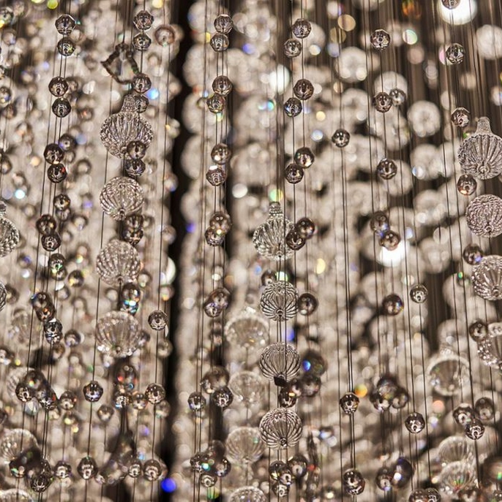 This is a large luxurious starry sky hanging crystal chandelier, supported by a circular metal frame with densely hanging crystal beads, presenting a brilliant starry effect, with both decorative and lighting functions, ideal for high-ceiling commercial spaces such as hotel lobbies and high-end clubs.