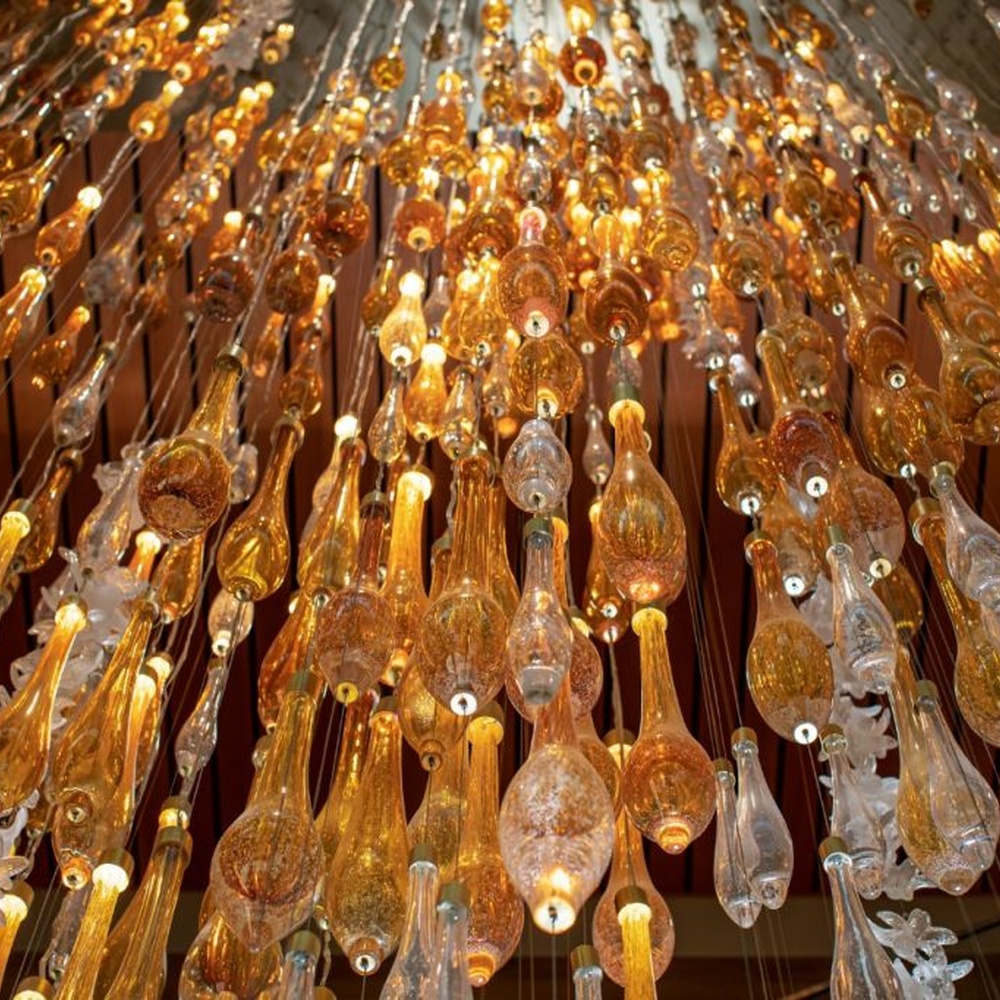 This is a natural-style suspended art installation lamp, composed of transparent ripple-shaped leaves and gold accents, creating an immersive scene with dead trees and green plants, with both decorative and lighting functions, ideal for weddings, high-end restaurants, art galleries and other scenarios.