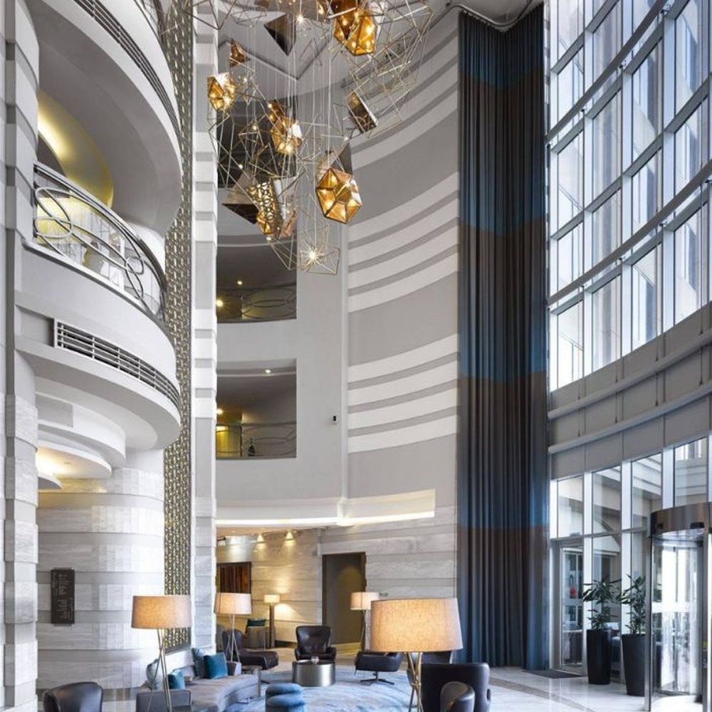This modern geometric art chandelier is composed of intertwined gold metal lines forming an abstract frame, paired with geometric-shaped liuli/acrylic ornaments. Light refracts through them to emit a brilliant halo, serving both lighting and installation art purposes, suitable for high-ceiling commercial spaces such as hotel lobbies and high-end clubs.