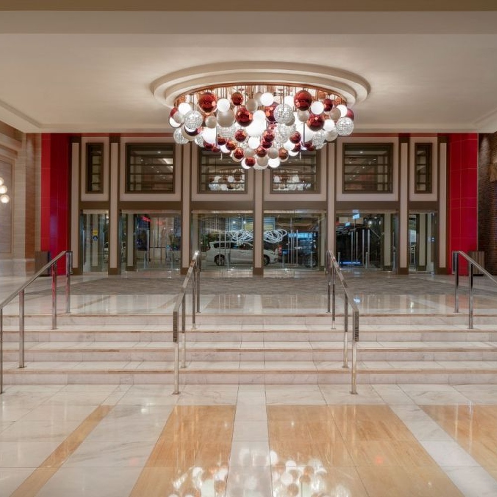 This is a modern luxury style cluster spherical chandelier, composed of red, white and silver glass balls arranged in a staggered manner, embedded in a circular ceiling structure, which has both lighting and artistic decoration functions, suitable for large commercial spaces such as hotel lobbies, shopping mall atriums, and high-end clubs.
