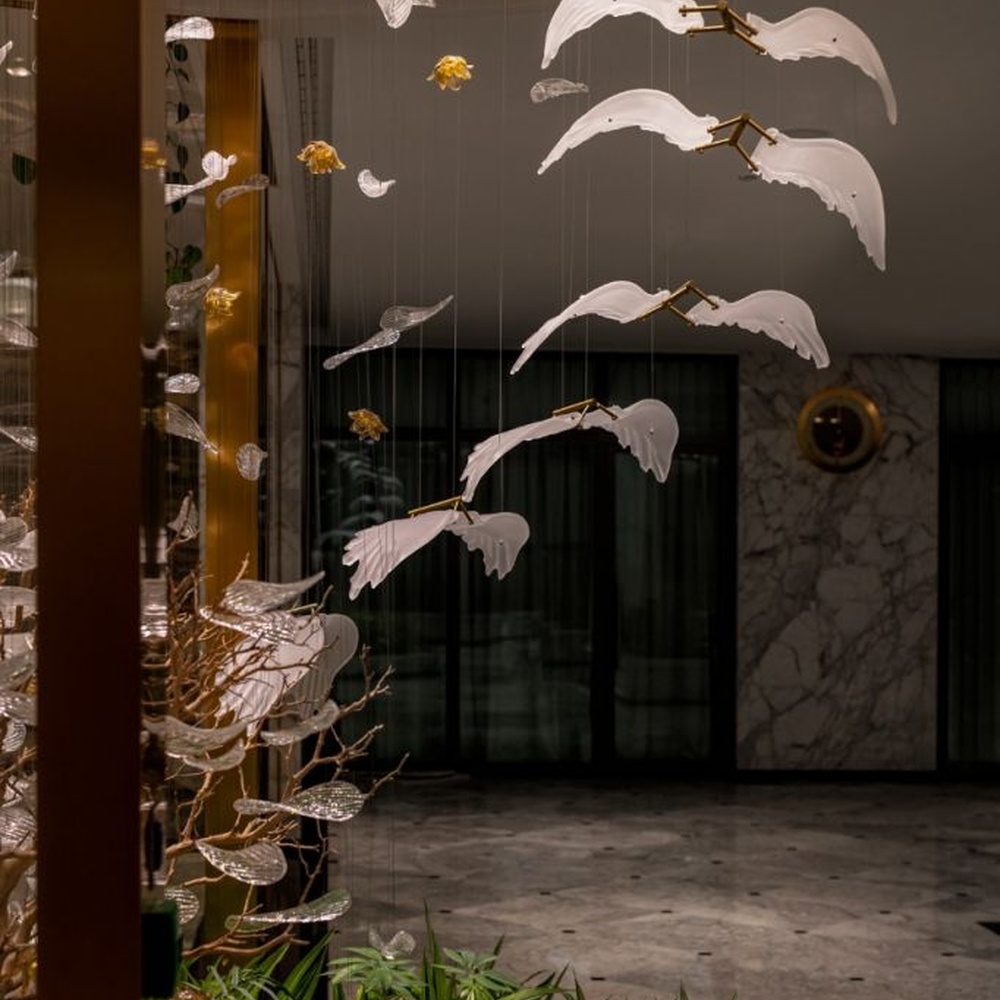 This is a natural-style suspended art installation lamp, composed of transparent ripple-shaped leaves and gold accents, creating an immersive scene with dead trees and green plants, with both decorative and lighting functions, ideal for weddings, high-end restaurants, art galleries and other scenarios.