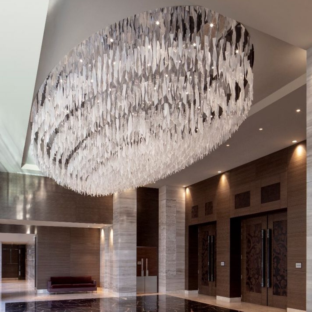 This large oval artistic chandelier is composed of a large number of transparent glass/acrylic pieces hung in a staggered manner, presenting a fluffy and soft visual effect like a cloud. The light refracts through the material to emit a brilliant and transparent glow, serving both lighting and decorative purposes, suitable for core decoration and lighting in large spaces such as hotel lobbies and high-end clubs.
