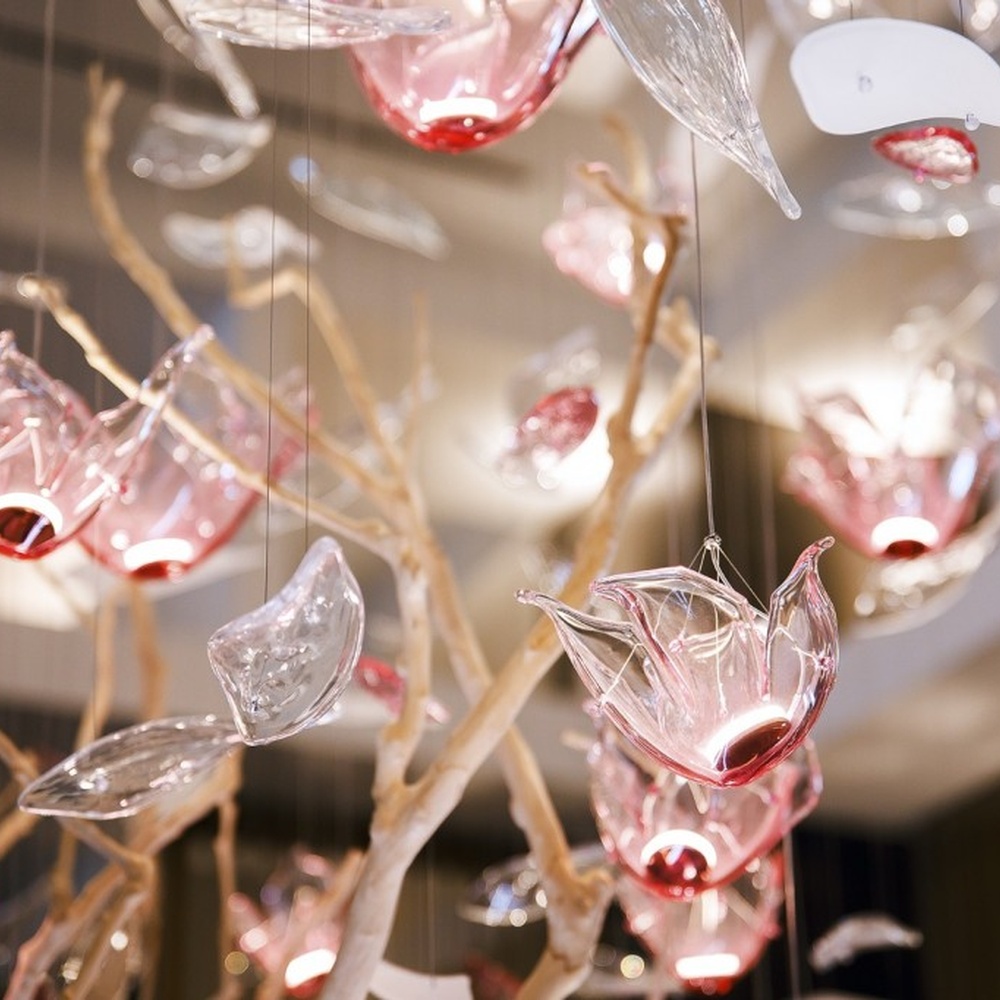 This is an art-installation style tree-shaped chandelier, with a simulated branch as the main structure, paired with transparent and pink-white gradient leaf-shaped luminous components, which has both artistic decoration and soft lighting functions, suitable for large commercial spaces such as hotel lobbies, high-end clubs, and art exhibition halls.