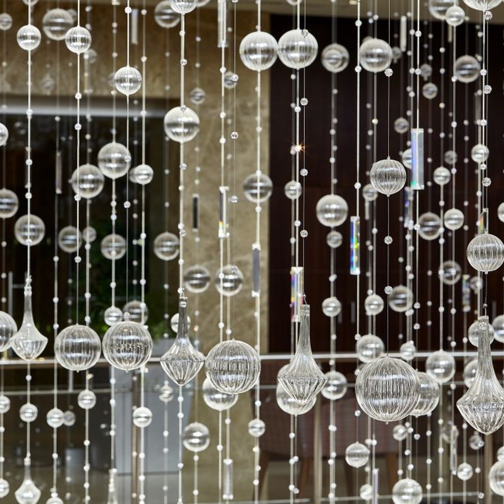 This large artistic bubble chandelier is composed of a large number of transparent glass bubble balls hung in a staggered manner by metal wires, presenting a visual effect like scattered starry sky. The light refracts through the bubbles to emit soft and transparent light spots, serving both lighting and decorative purposes, suitable for high-ceiling commercial spaces such as hotel lobbies and shopping mall atriums.