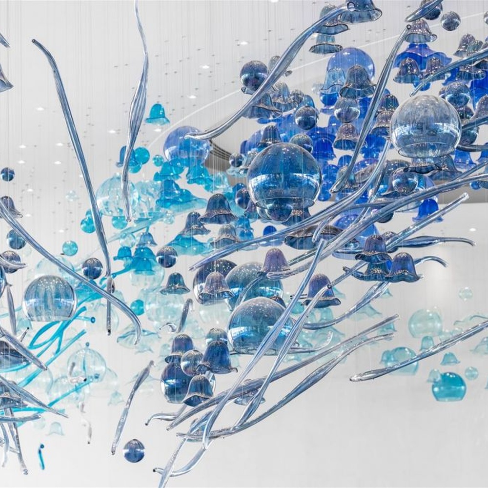 This blue-tone liuli bubble art chandelier is composed of gradient blue and transparent glass bubbles intertwined with metal lines, presenting a dynamic shape like marine plankton. Light refracts through the liuli to emit a transparent and soft halo, serving both lighting and installation art purposes, suitable for high-end commercial spaces such as hotel lobbies and art exhibition halls.